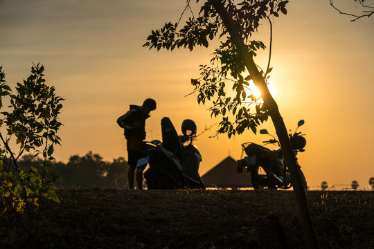 Silhouette of a man with motorcycles during beautiful golden sunset, road trip lifestyle.