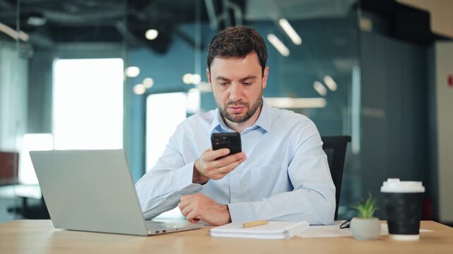 Close-up of businessman or IT specialist dictating audio note on cellphone. Corporate worker, manager or freelance designer using mobile app voice control at contemporary coworking workspace.