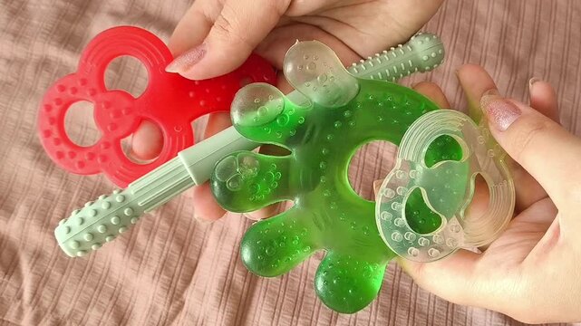 Teethers for children in women's hands against the background of children's teethers. Teething period in children.