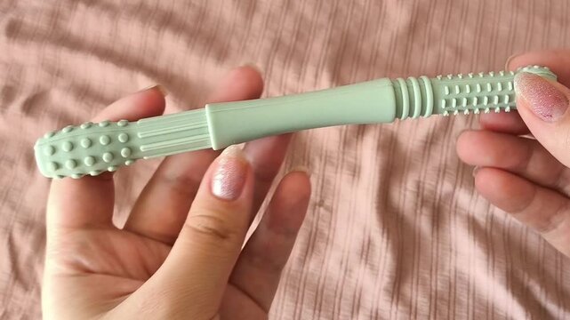 Teether for children in a woman's hand against the background of a crib