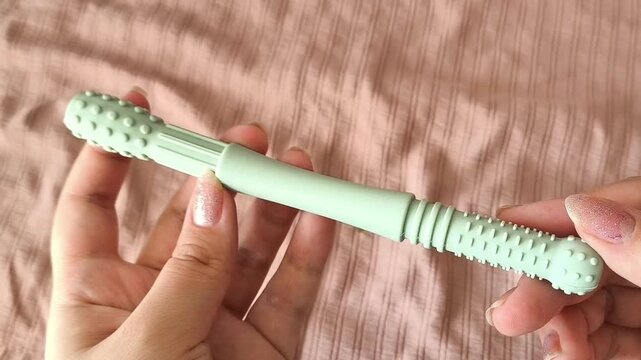 Teether for children in a woman's hand against the background of a crib
