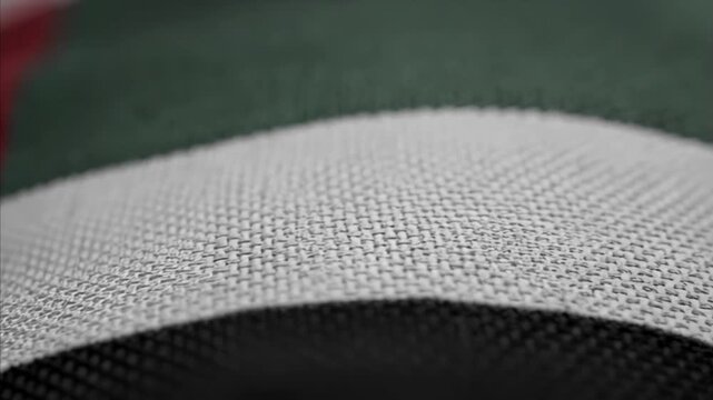 Close-up fabric texture detail of United Arab Emirates flag with waving motion showing horizontal stripes of red, green, white, and black colors, representing national pride and identity.