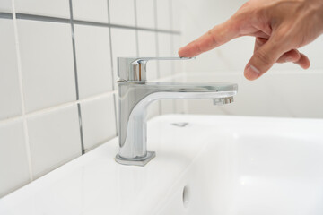 Fototapeta premium Save water. Man keeps turning off the running water in the bathroom to protect environment. Greening planet, reduce global warming, Save world, life, future, risk energy, crisis , water day.
