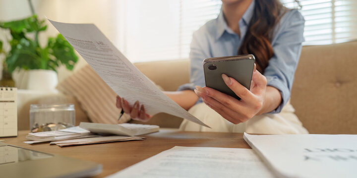 Person reviewing financial documents and using smartphone at home