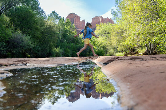 Lone girl jumping over reflecting pool outdoors wilderness
