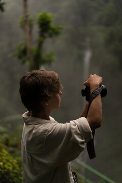 Woman photographer shooting misty waterfall in jungle, Sekumpul, Bali
