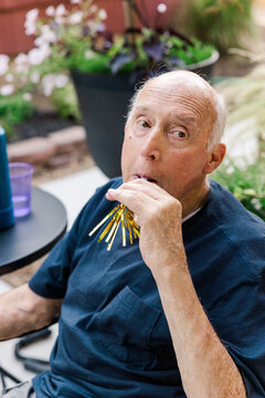Elderly man celebrating outdoors with party blower