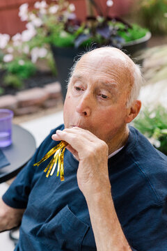 Senior man celebrating outdoors with party blower