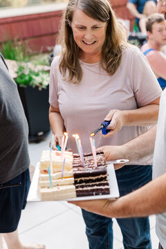 Woman lighting candles on birthday cake