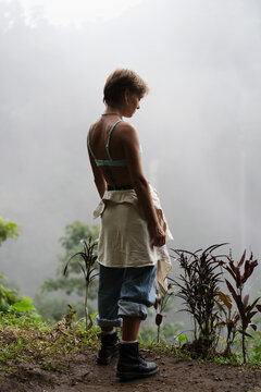 Woman standing back to camera looking down in misty jungle, Bali