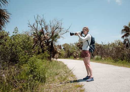 Woman with big camera bird watches in Florida Everglades