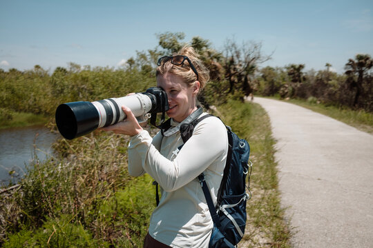 female birdwatcher takes photo while hiking in Florida Everglades