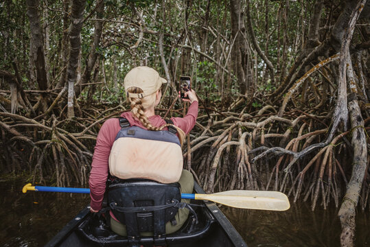 woman takes selfie from canoe in mangrove forest in Everglades