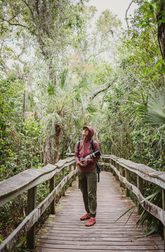 Woman with large camera walks on boardwalk in Everglades, Florida