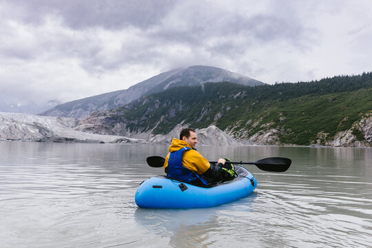 Man in blow up kayak paddling in glacial lake in Alaska