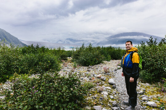 Man hiking over rocky terrain near glaciers and mountains