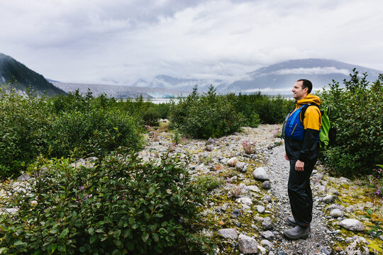 Man on adventure on hike path in Alaska with glacier and mountain