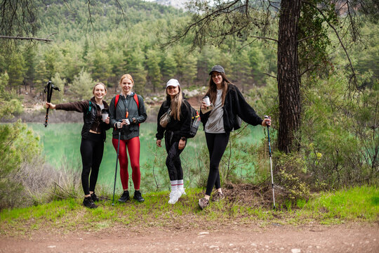 Happy female hikers posing by a green lake
