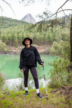 Happy young woman hiking near a mountain lake