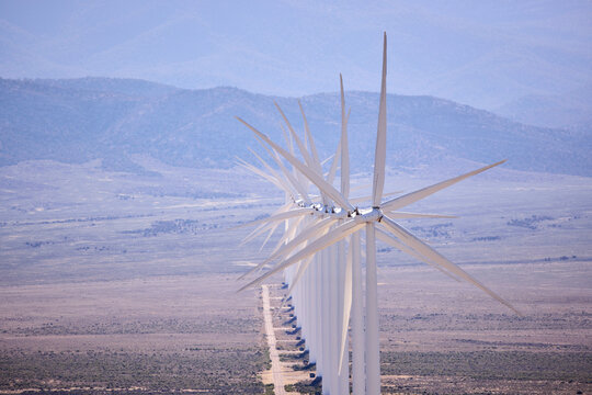 A long line of wind turbines in a desert landscape