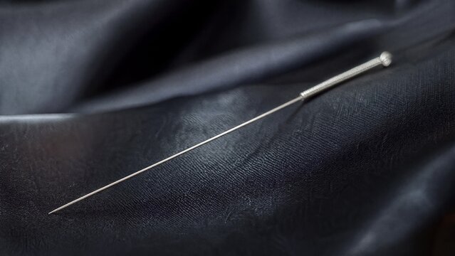acupuncture. Slender silver acupuncture needle on dark silk fabric. STEM education sheets, lab safety posters, designed for STEM education and laboratory safety posters.