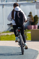 Obraz premium Back view of cyclist on paved path near modern buildings and plants