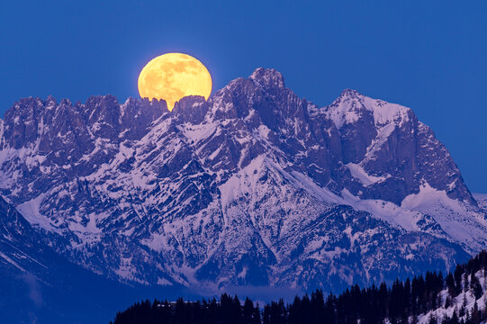 Austria, Tyrol, Yellow moon rising over Wiedersberger Horn at dusk