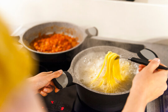 Woman preparing spaghetti, trying if they are ready to eat