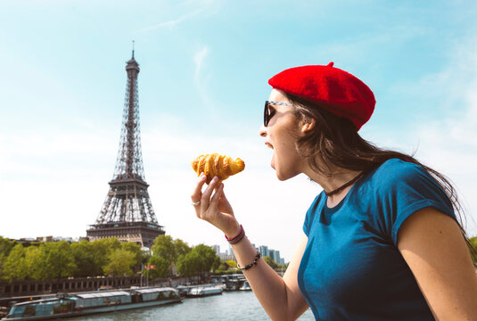 France, Paris, woman eating croissant in front of Seine river and Eiffel Tower