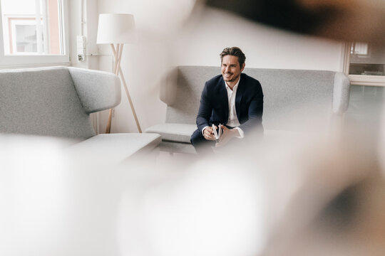 Smiling businessman with notebook on couch