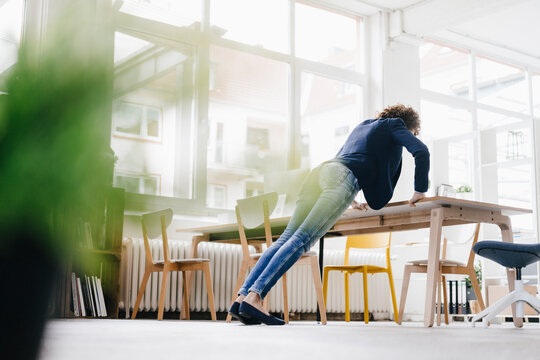 Businesswoman in office doing push ups on desk