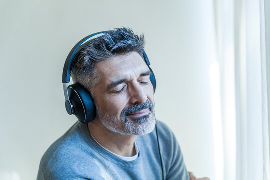 Mature man with closed eyes wearing headphones
