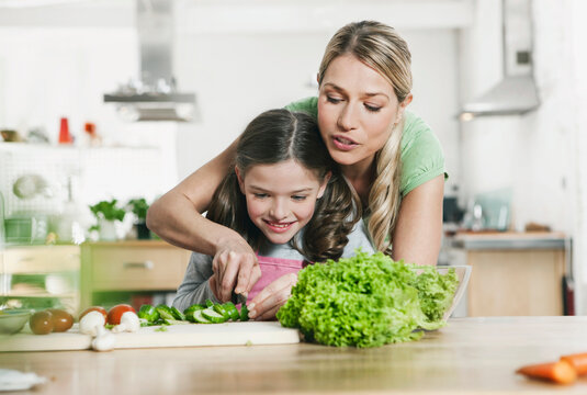 Germany, Cologne, Mother and daughter preparing salad