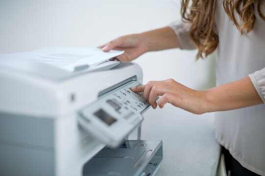 Office worker pressing button of a printetr