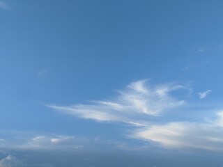 Fototapeta premium Clear blue sky filled with soft white wispy cirrus clouds. Natural sky background perfect for graphic design, background, wallpaper, and presentation backdrop.