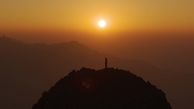 4K drone footage of a traveler standing high above the Himalayas during a vibrant sunrise in Uttarakhand.
