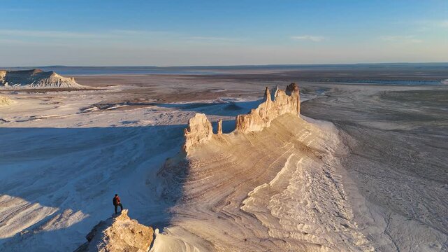 a man stands and watches the sunset in Bozzhyra is a tract in the western part of the Ustyurt Plateau on the Mangyshlak Peninsula in the Mangystau Region of Kazakhstan