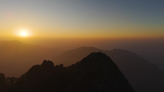 4K scenic sunrise footage with a boy overlooking Himalayan valleys from a rocky cliff in India.