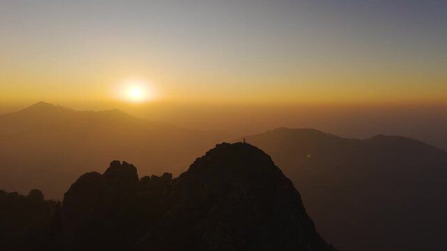 4K cinematic drone shot of a traveler standing against colorful sunrise skies in Uttarakhand.