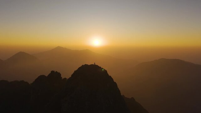 4K aerial footage of a boy watching the sunrise from a high-altitude Himalayan mountain ridge.
