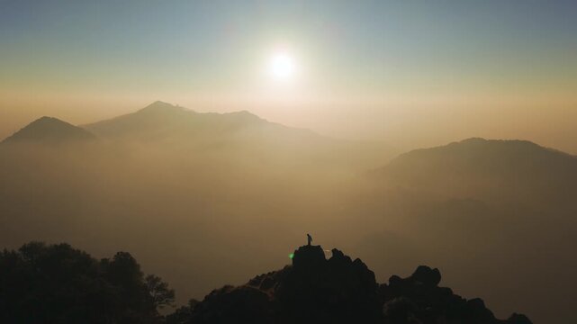 4K scenic drone footage of a traveler standing above clouds during Himalayan sunrise in India.