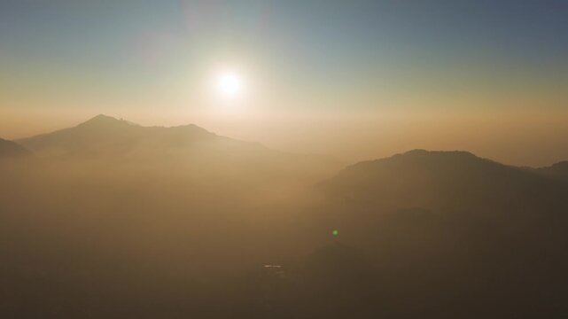 4K drone shot of a boy standing on top of a rocky mountain with scenic Himalayan sunrise in Uttarakhand, India.