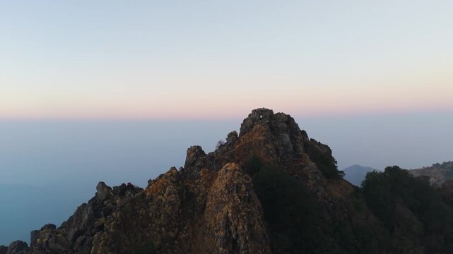 4K drone footage capturing a boy climbing toward a mountain summit during golden sunrise in Uttarakhand.