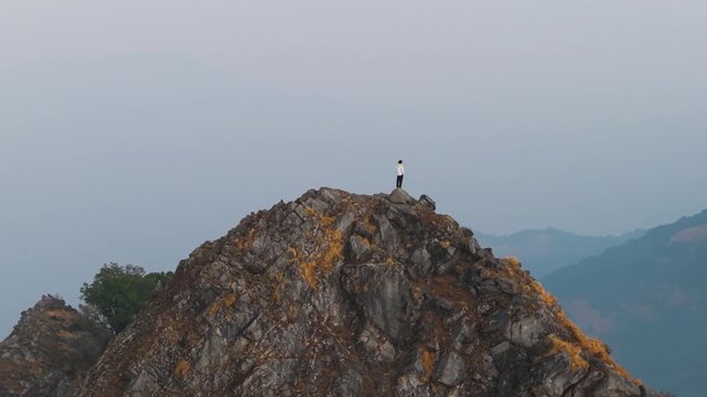 4K cinematic 360 drone footage of a traveler standing on a Himalayan cliff with vibrant sunrise skies in Uttarakhand.