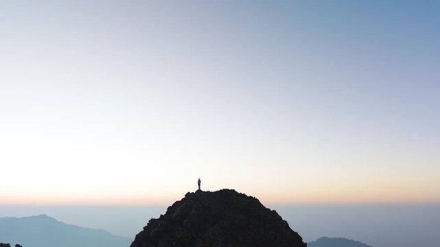 4K 360 drone shot of a boy overlooking scenic Himalayan mountain ranges during colorful sunrise in Uttarakhand.