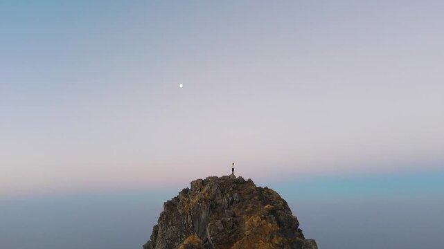 4K sunrise 360 drone shot of a boy standing on a rocky ridge with breathtaking Himalayan landscape in Uttarakhand.