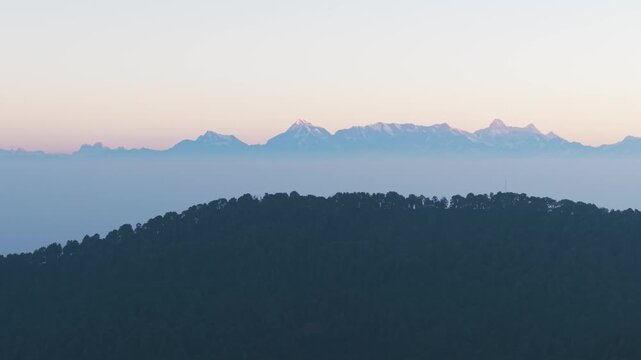 4K cinematic drone footage of the Uttarakhand Himalayan range glowing under morning sunlight at sunrise, India.