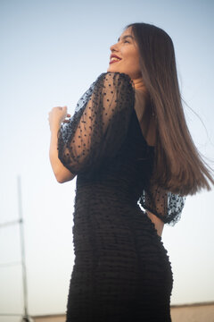 Beautiful and sensual young woman in a dress on a building rooftop in the golden hour