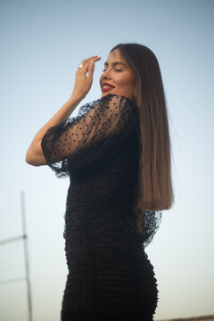 Beautiful and sensual young woman in a dress on a building rooftop in the golden hour