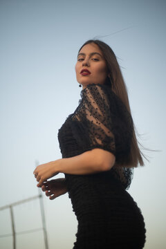 Beautiful and sensual young woman in a dress on a building rooftop in the golden hour